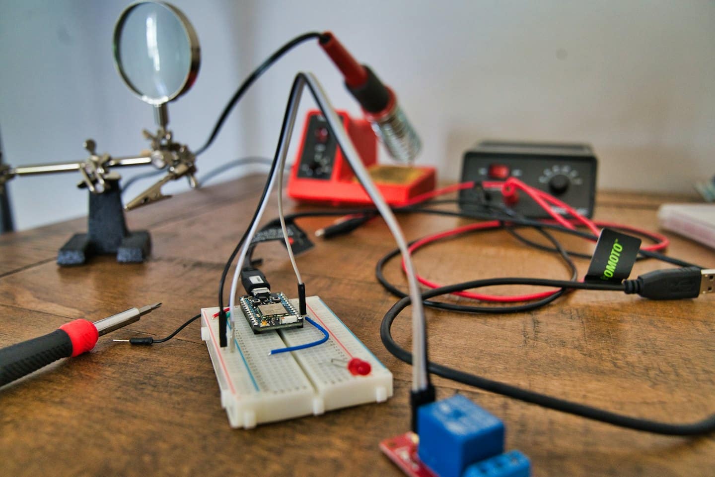 Elektronická pracovná doska s nepájivým poľom, náradím a komponentmi pre DIY projekt.